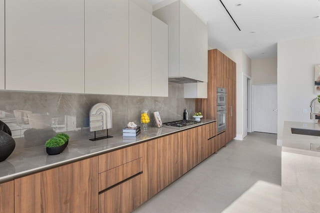 kitchen with backsplash, white cabinetry, sink, and stainless steel appliances