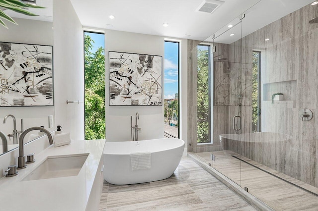 bathroom featuring shower with separate bathtub, vanity, and a wall of windows