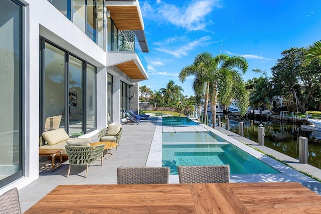 view of pool featuring a patio area, a water view, and an in ground hot tub