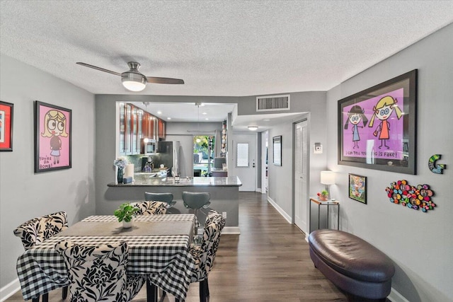 dining area featuring a textured ceiling, ceiling fan, and dark wood-type flooring