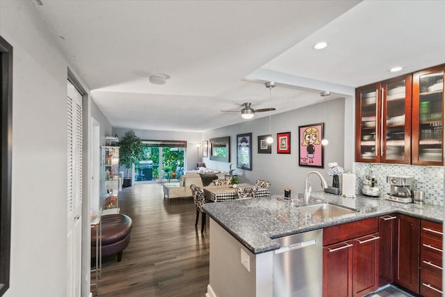 kitchen with sink, stainless steel dishwasher, dark hardwood / wood-style floors, dark stone countertops, and tasteful backsplash