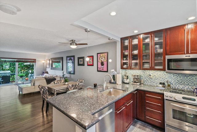 kitchen with stone counters, kitchen peninsula, sink, and appliances with stainless steel finishes