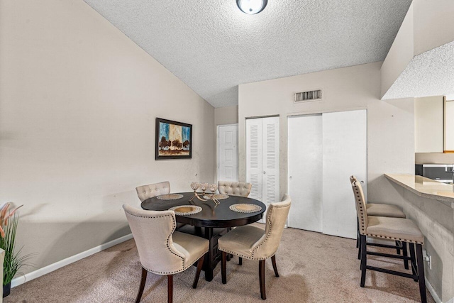 carpeted dining space featuring lofted ceiling and a textured ceiling