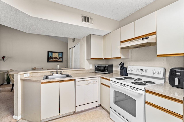 kitchen with white appliances, white cabinets, sink, a textured ceiling, and kitchen peninsula