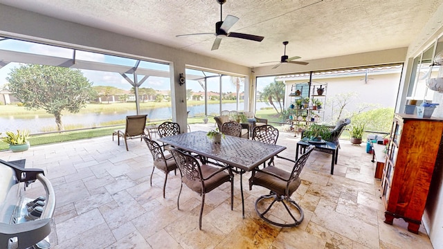 sunroom featuring ceiling fan and a water view