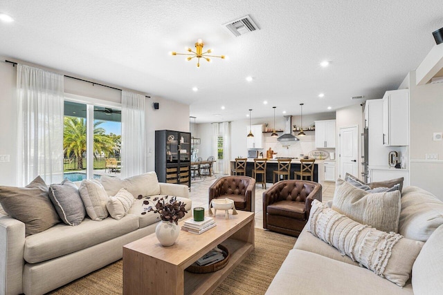 living room with light wood-type flooring, a textured ceiling, and an inviting chandelier