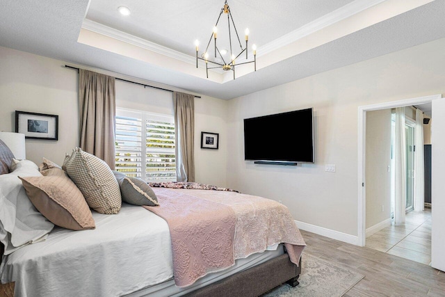 bedroom with a chandelier, a raised ceiling, light hardwood / wood-style flooring, and ornamental molding