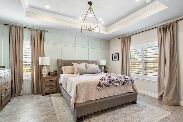 bedroom featuring light hardwood / wood-style flooring, multiple windows, and a tray ceiling