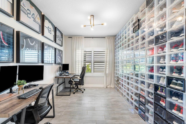 office space with light wood-type flooring, a textured ceiling, and a notable chandelier