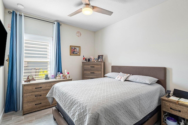 bedroom with a textured ceiling, light hardwood / wood-style flooring, and ceiling fan