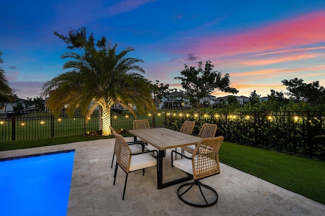 patio terrace at dusk with a fenced in pool and a lawn