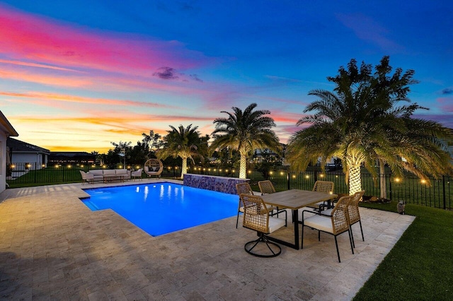 pool at dusk with a lawn, pool water feature, and a patio