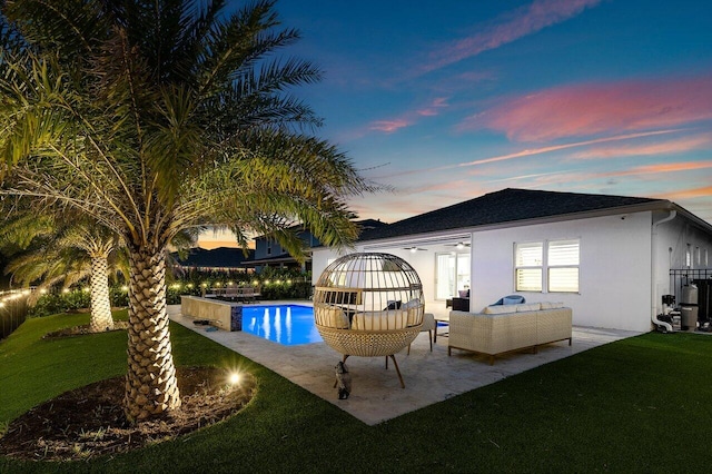 pool at dusk featuring outdoor lounge area, a yard, and a patio