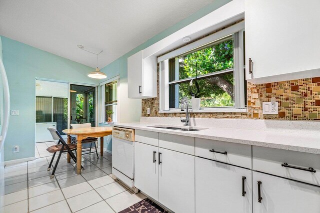 kitchen featuring backsplash, white dishwasher, sink, pendant lighting, and white cabinetry