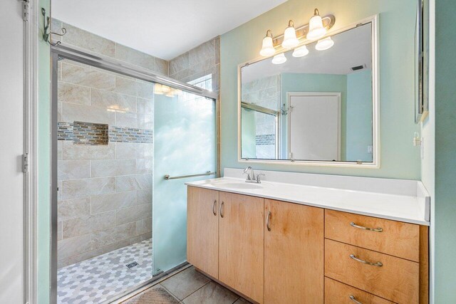 bathroom with tile patterned flooring, vanity, and a shower with shower door