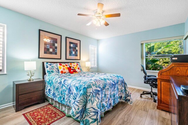 bedroom with ceiling fan, light wood-type flooring, and a textured ceiling