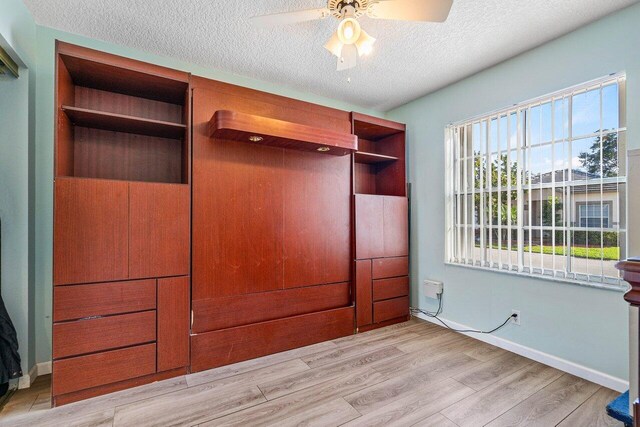 unfurnished bedroom featuring a textured ceiling, light wood-type flooring, and ceiling fan