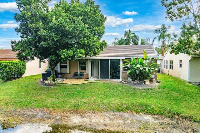 back of property with a lawn and a sunroom