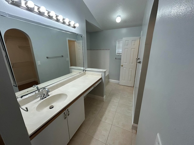 bathroom with tile patterned floors, vanity, and vaulted ceiling