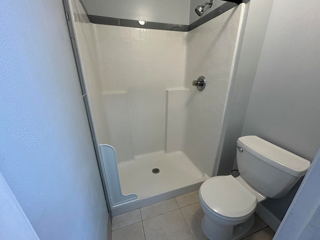 bathroom with a shower, tile patterned flooring, and toilet