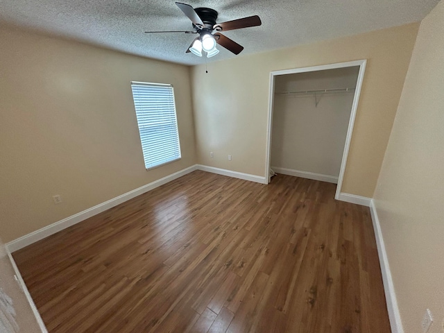 unfurnished bedroom with wood-type flooring, a textured ceiling, a closet, and ceiling fan