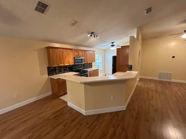 kitchen featuring kitchen peninsula, tasteful backsplash, a textured ceiling, stainless steel appliances, and hardwood / wood-style floors