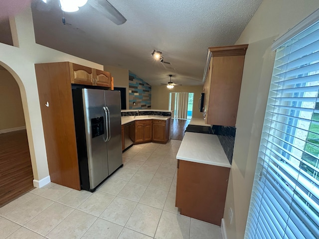 kitchen with a textured ceiling, a wealth of natural light, lofted ceiling, and appliances with stainless steel finishes