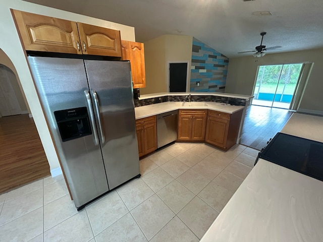 kitchen with ceiling fan, stainless steel appliances, vaulted ceiling, and light hardwood / wood-style floors