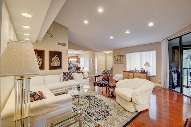 living room with wood-type flooring, vaulted ceiling, and an inviting chandelier