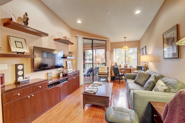 living room with a textured ceiling, light hardwood / wood-style flooring, and lofted ceiling