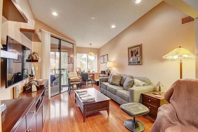 living room featuring high vaulted ceiling, light hardwood / wood-style floors, and a textured ceiling