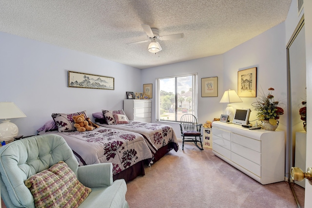 bedroom featuring ceiling fan, light colored carpet, and a textured ceiling