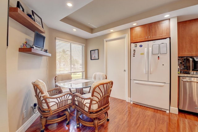 dining space featuring light hardwood / wood-style floors and a tray ceiling