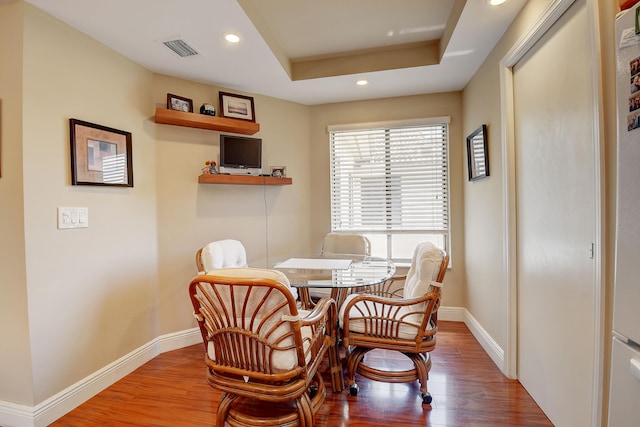 dining area featuring a tray ceiling and hardwood / wood-style flooring