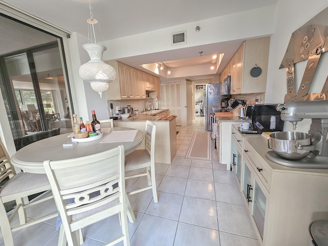 kitchen featuring decorative backsplash, appliances with stainless steel finishes, sink, light tile patterned floors, and hanging light fixtures