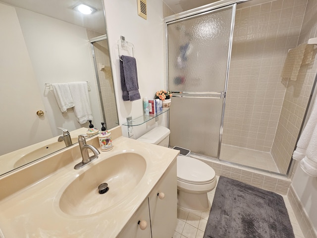 bathroom with toilet, vanity, tile patterned floors, and a shower with door