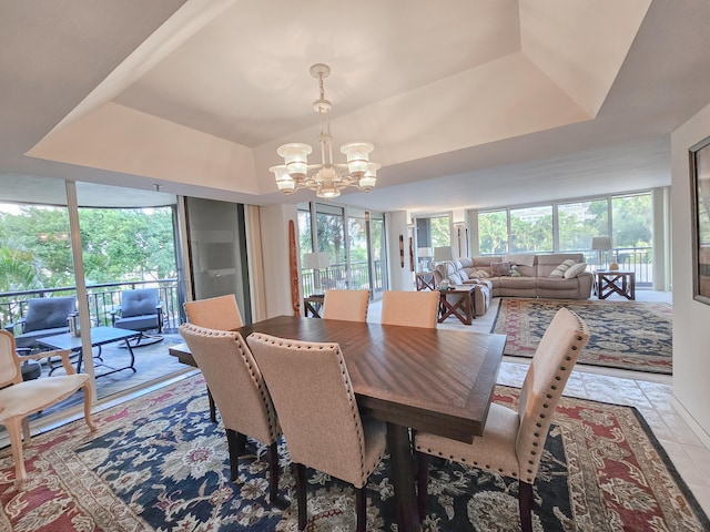 dining area with a chandelier, a tray ceiling, and plenty of natural light