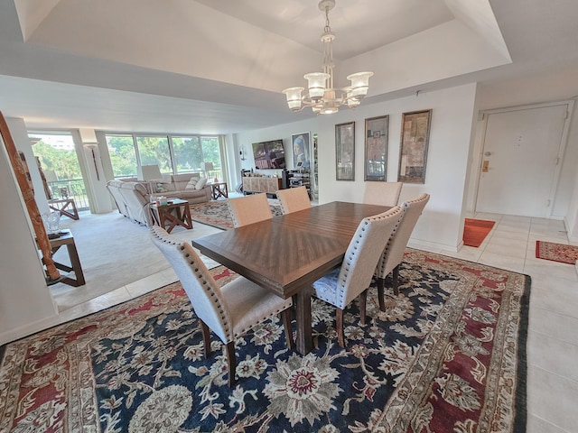 tiled dining space with plenty of natural light, an inviting chandelier, and a tray ceiling