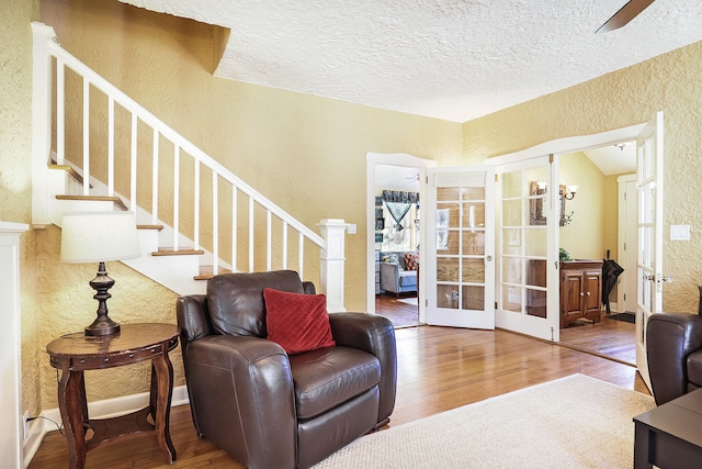 living area with french doors, a textured ceiling, and hardwood / wood-style flooring