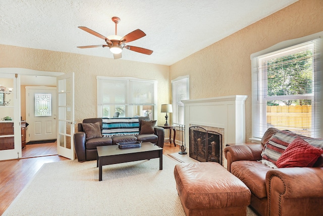 living room with ceiling fan, light hardwood / wood-style flooring, and a textured ceiling