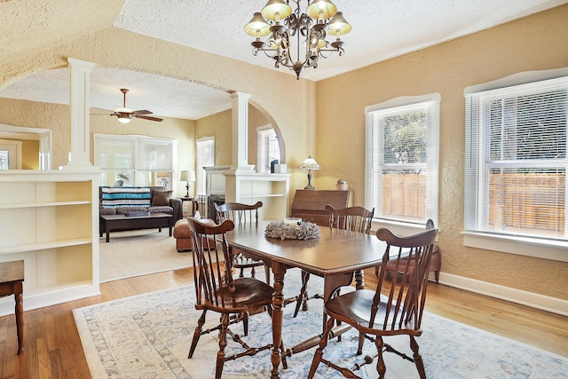 dining space featuring ornate columns, ceiling fan with notable chandelier, a textured ceiling, vaulted ceiling, and hardwood / wood-style floors