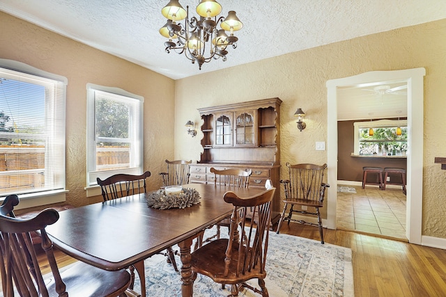 dining space with wood-type flooring, a textured ceiling, and an inviting chandelier