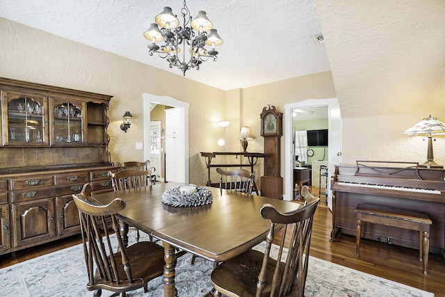 dining area with a chandelier, a textured ceiling, and dark wood-type flooring