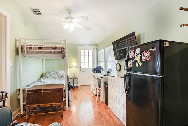 bedroom with ceiling fan, vaulted ceiling, light hardwood / wood-style flooring, and fridge