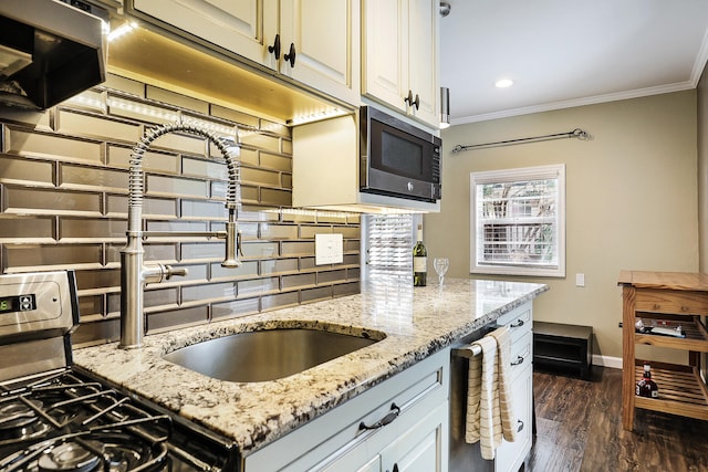 kitchen with appliances with stainless steel finishes, dark hardwood / wood-style flooring, light stone counters, and crown molding