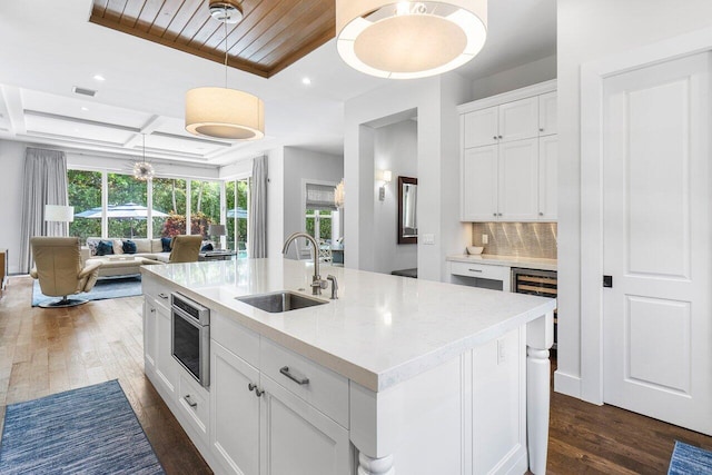 kitchen featuring sink, hanging light fixtures, dark hardwood / wood-style flooring, an island with sink, and white cabinets