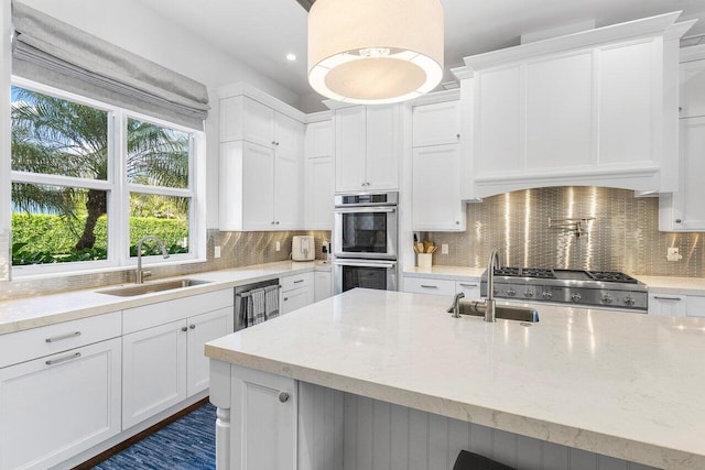 kitchen featuring white cabinets, appliances with stainless steel finishes, light stone counters, and sink