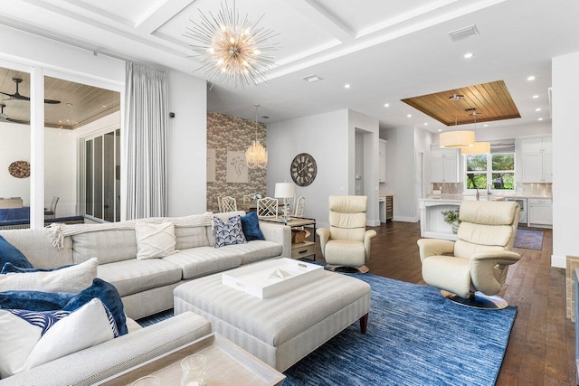 living room featuring dark wood-type flooring, coffered ceiling, and an inviting chandelier