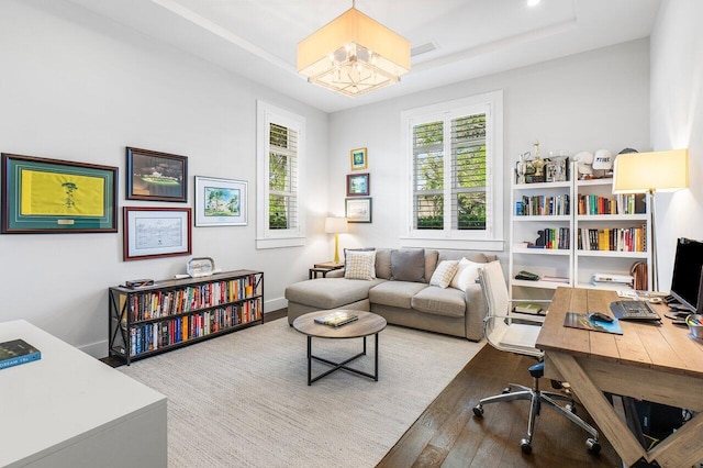 office area with a chandelier, hardwood / wood-style floors, and a raised ceiling