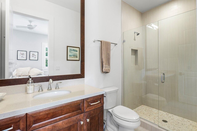 bathroom with vanity, ceiling fan, toilet, and a shower with shower door